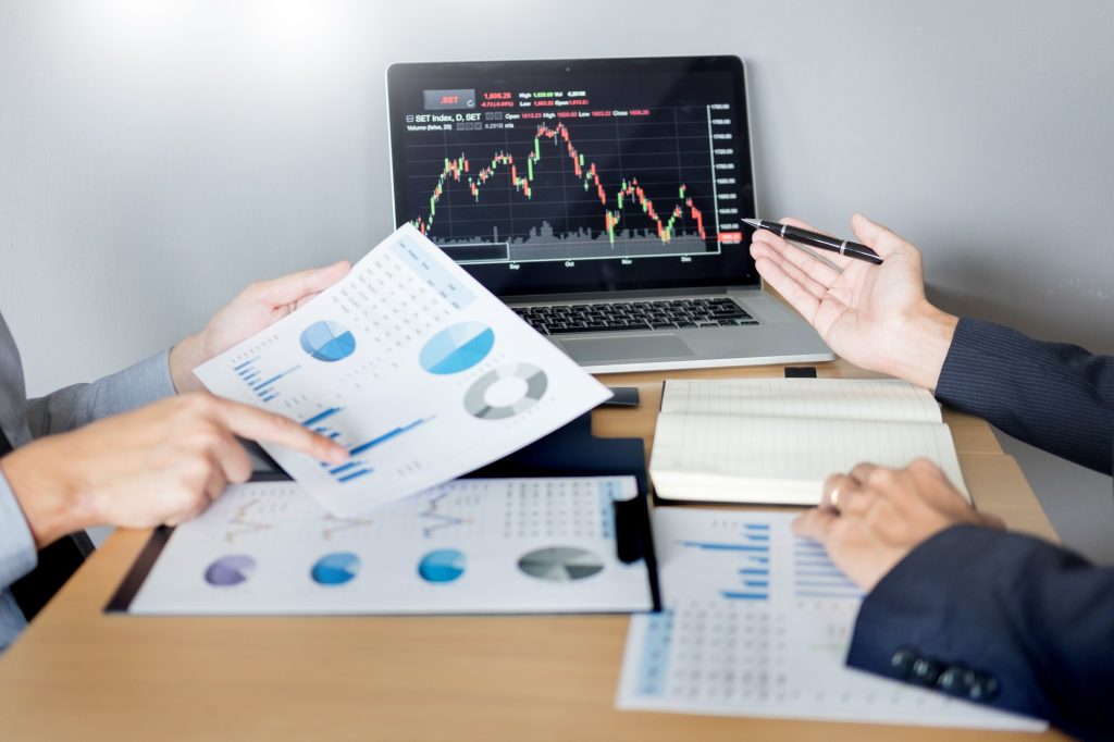 Stock traders looking at finance analysis marketing report trading stocks online in office